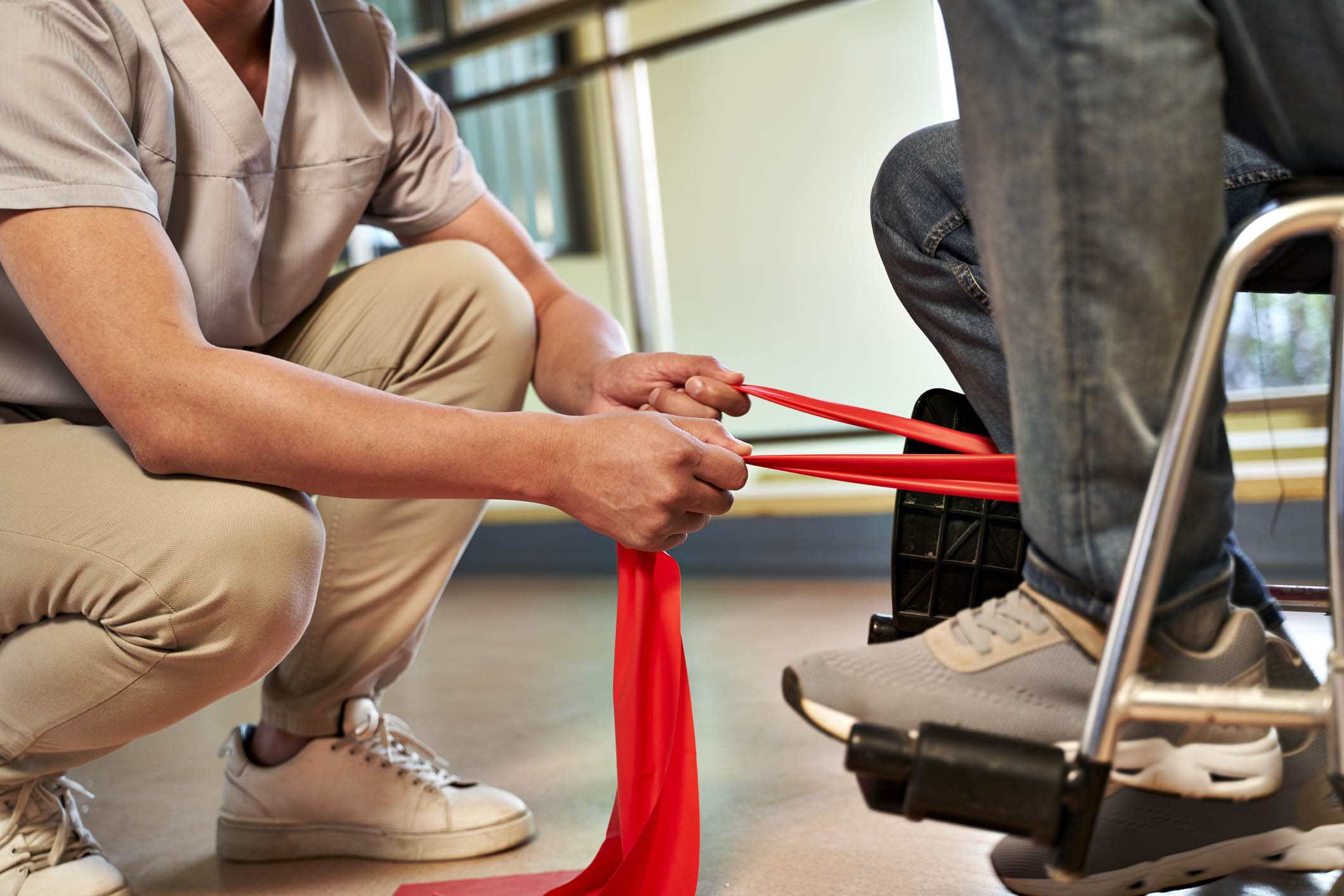 young asian physical therapist working with senior patient using resistance band