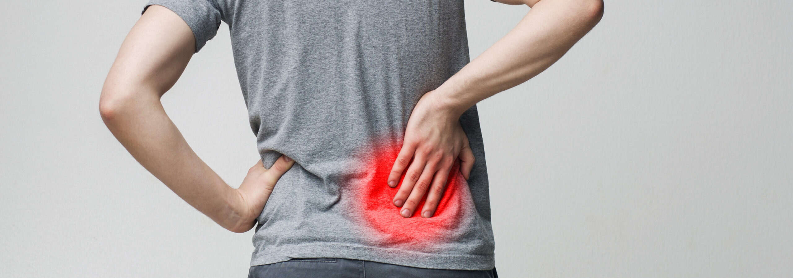 Young man holding his painful inflamed loin Lumbago symptom. Young man holding his painful inflamed loin, panorama, empty space